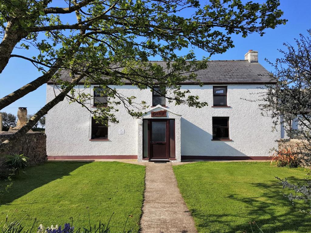 a white house with a door in the yard at Spacious 3-Bedroom 3-bathroom country cottage in Haverfordwest