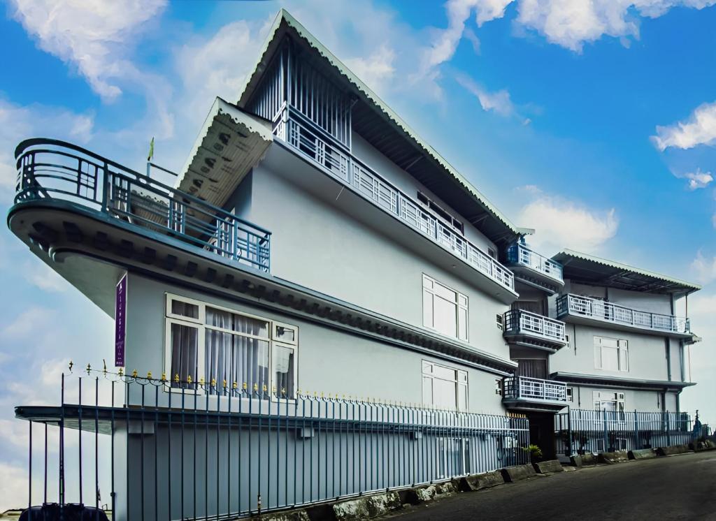 - un bâtiment blanc avec des balcons sur le côté dans l'établissement Mount Lungta Boutique Hotel & Spa, à Darjeeling