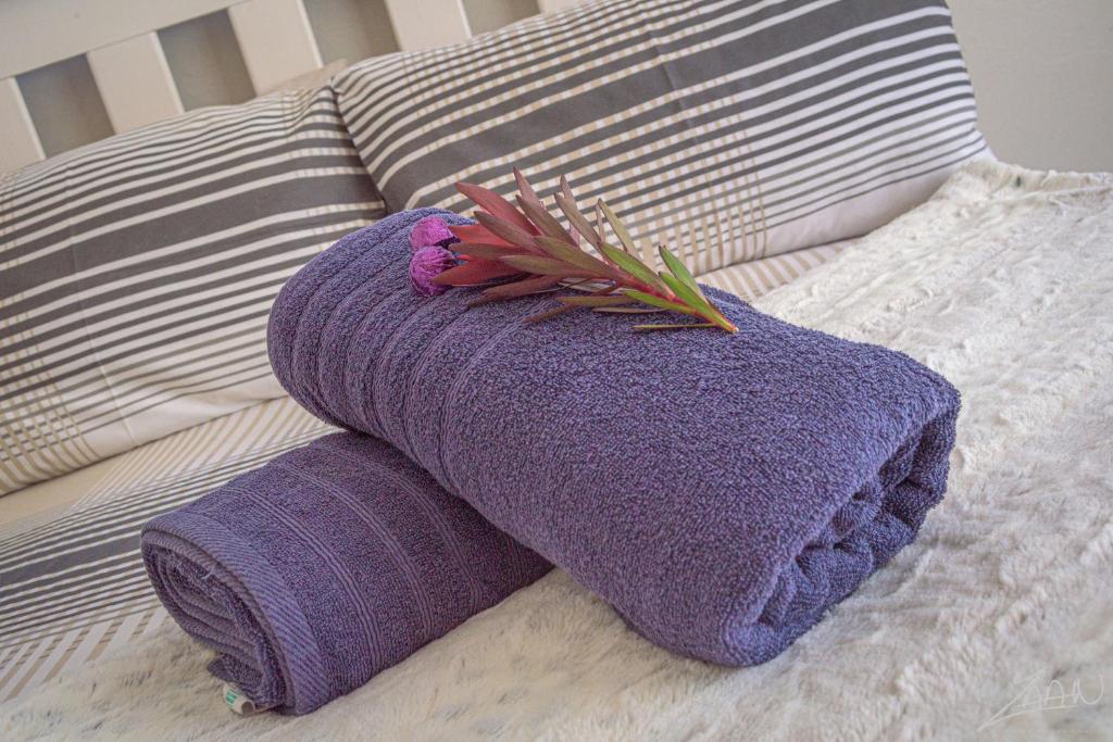 - une serviette violette et une fleur sur le lit dans l'établissement Fynbos Golf and Country Estate, à Eersterivierstrand