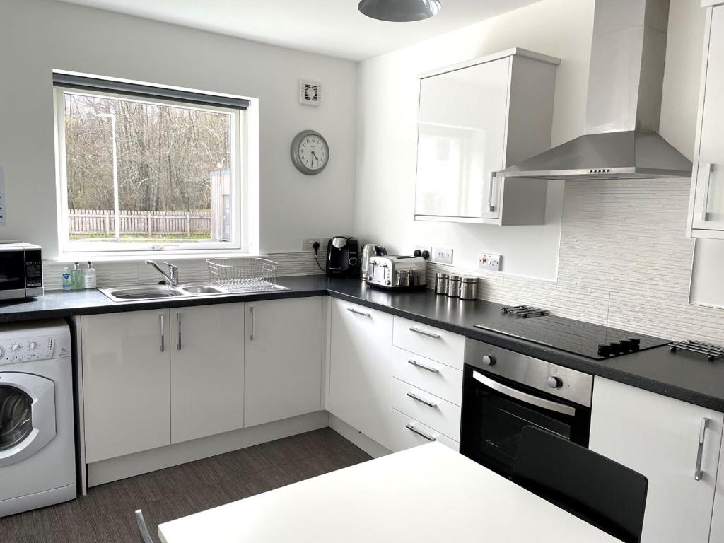 a kitchen with white cabinets and a sink and a window at Millwood in Aviemore