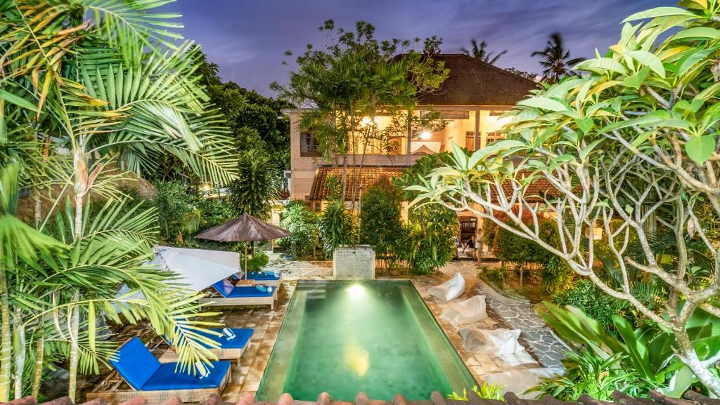 a swimming pool in a garden with palm trees at Cafe Wayan Cottages Senggigi in Senggigi 