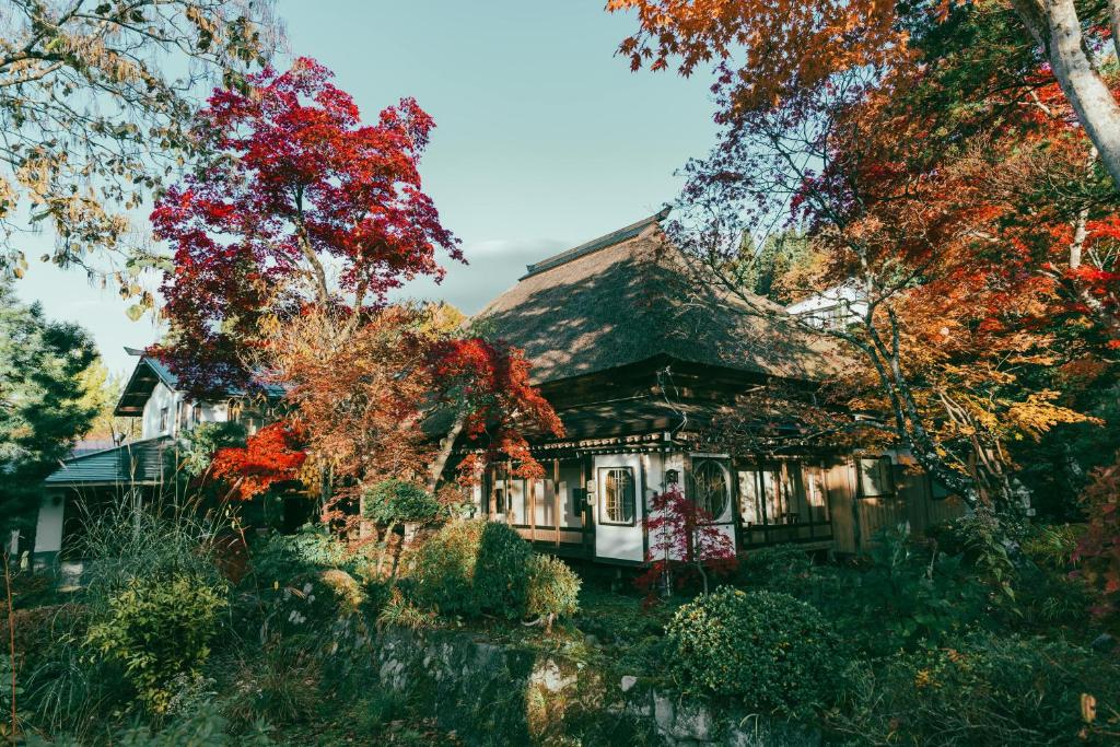 ein von Bäumen umgebenes Haus im Herbst in der Unterkunft Kyufukujyuin Takei Ryokan in Nagano