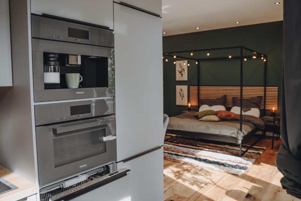a kitchen with a built in oven and a bedroom at EDLER WOHNRAUM Luxuriöses Studio im Zentrum mit Parkplatz, Einbaukaffeevollautomat, Netflix & Klimaanlage in Zwickau