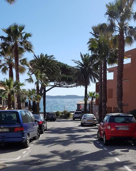 une rue avec des voitures garées, des palmiers et l'océan dans l'établissement IDEAL : Mer et centre ville à 2 pas +un garage, à Sainte-Maxime