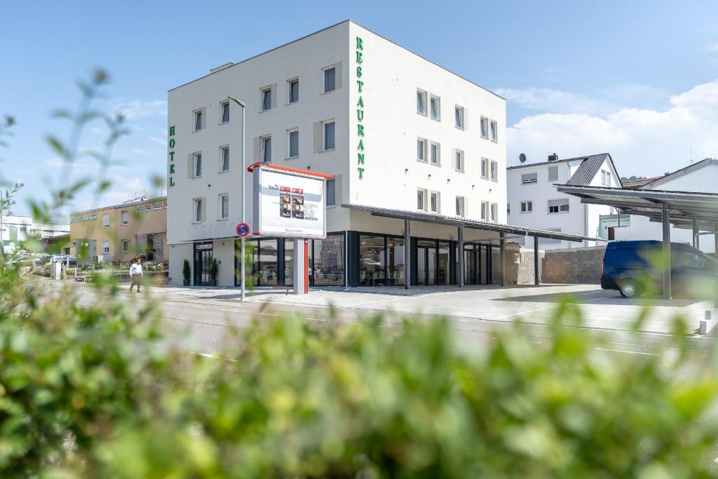 un bâtiment blanc avec un panneau devant lui dans l'établissement Hotel in Laisen, à Reutlingen