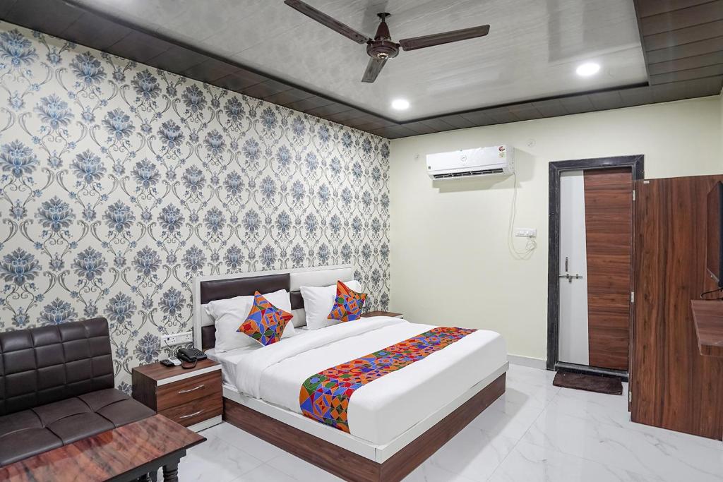 a bedroom with a bed and a chair in it at FabHotel Rajdhani in Kānpur