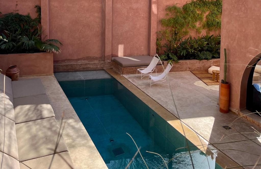 uma piscina com duas cadeiras e uma mesa em Maison Brummell Majorelle em Marrakech