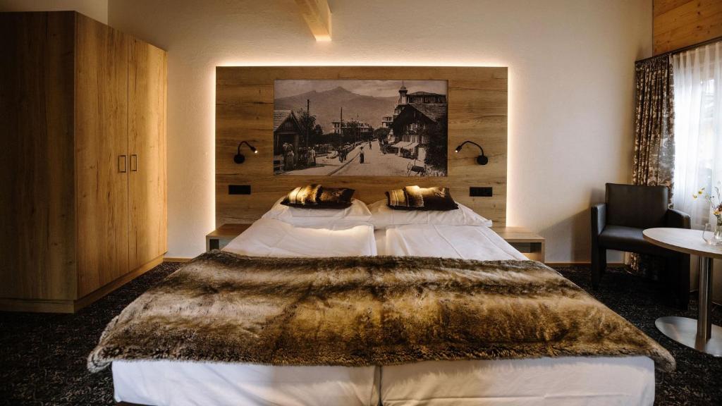a bedroom with a large bed with a painting on the wall at Hotel PINTE in Grindelwald