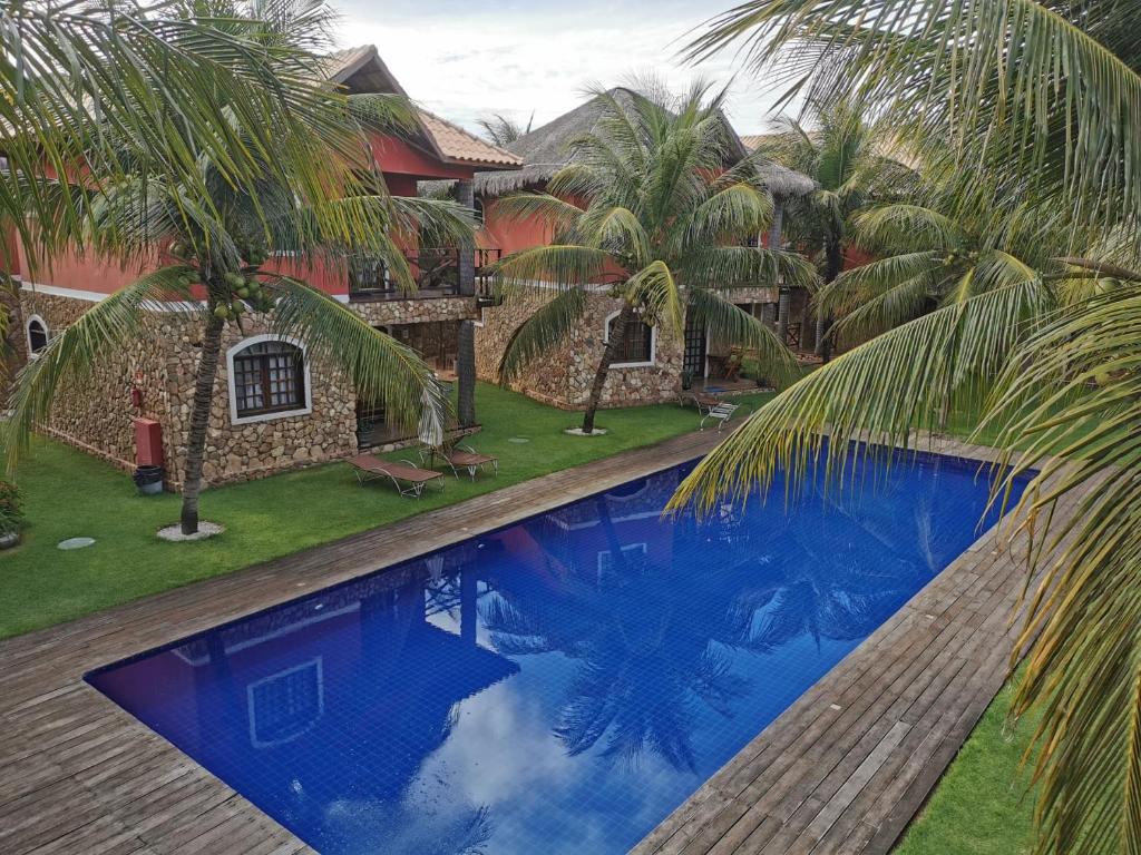 una piscina frente a una casa con palmeras en Chale Canoa Quebrada La Fazenda, en Canoa Quebrada