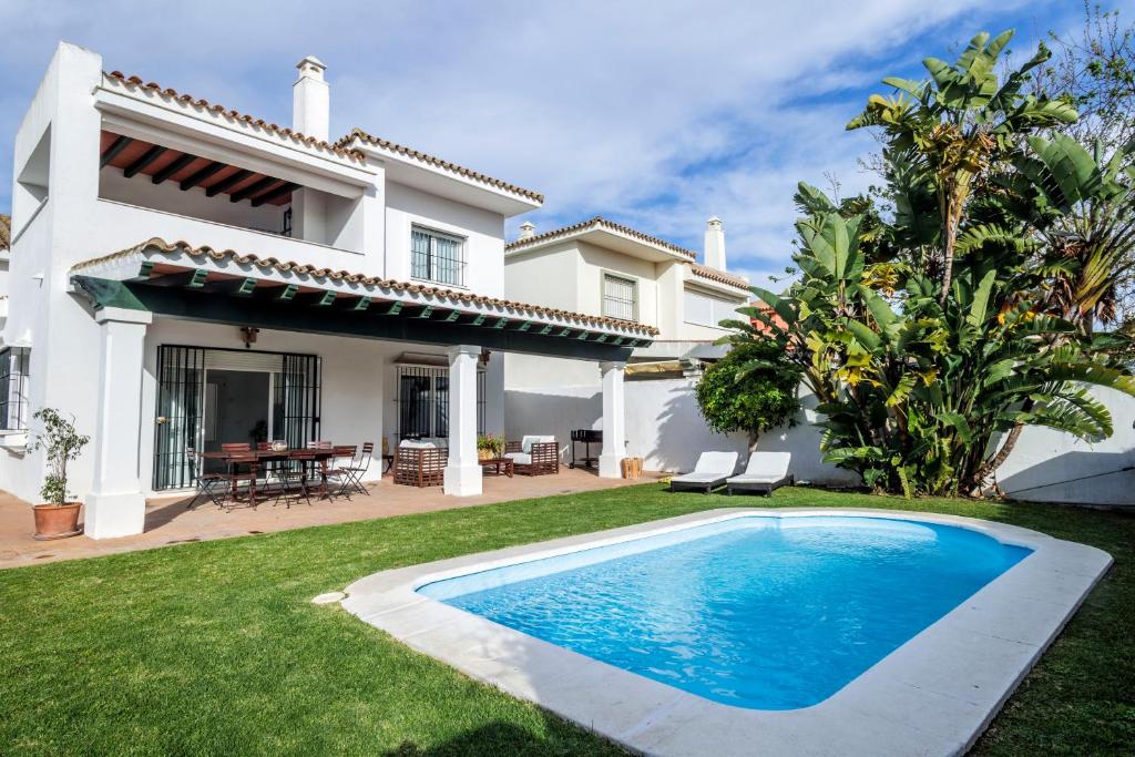 a villa with a swimming pool in front of a house at GINVA - Villa Puerto Sherry in El Puerto de Santa María