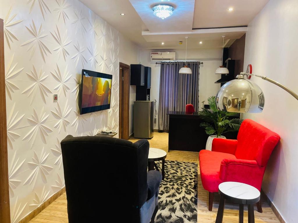 a living room with two chairs and a red couch at James Court Hotel & Luxury Apartments in Lekki