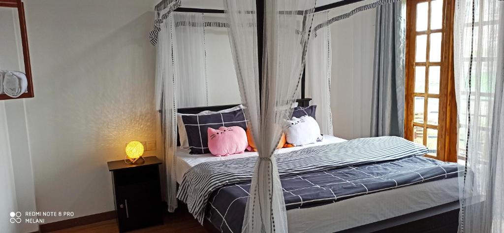 um quarto com uma cama de dossel e almofadas cor-de-rosa em Mount Elegence em Nuwara Eliya