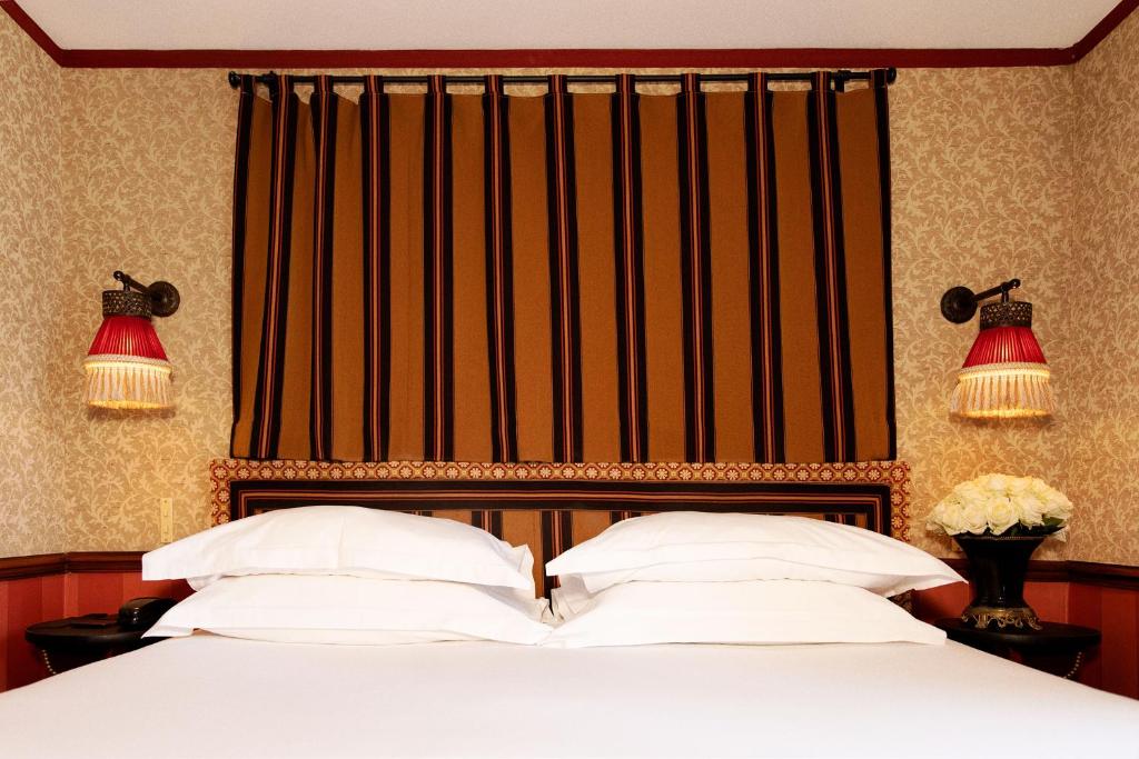 a bed with two white pillows and a large window at Hôtel Bourg Tibourg in Paris