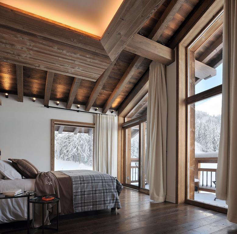 a bedroom with wooden ceilings and a bed and windows at Chalet Le Moulin, Courchevel Le Praz, 6 chambres, Ski in, Ski out in Courchevel