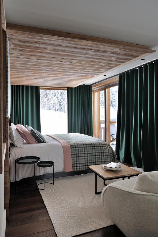 una camera da letto con un grande letto con tende verdi di Chalet Le Moulin, Courchevel Le Praz, 6 chambres, Ski in, Ski out a Courchevel