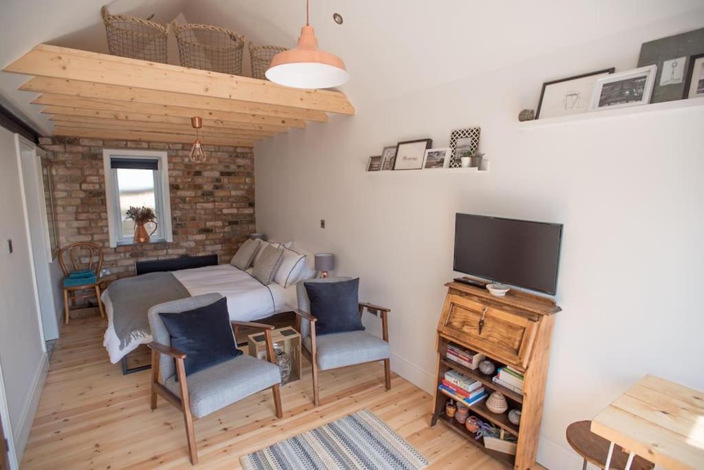 um quarto com uma cama e duas cadeiras e uma televisão em Cwtch, cozy studio, private, separate entrance. em Cardiff