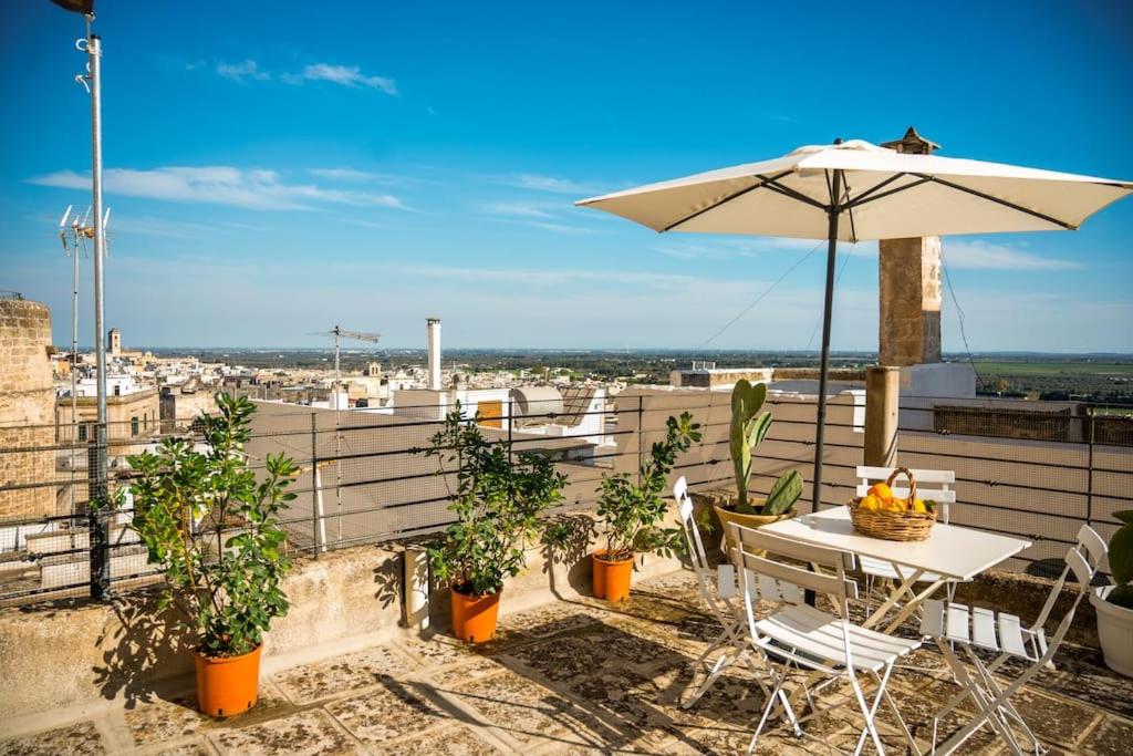 une table et un parasol sur un balcon avec des plantes dans l'établissement [Borgo Antico-Centro Storico] Casa Ventosa, à Oria