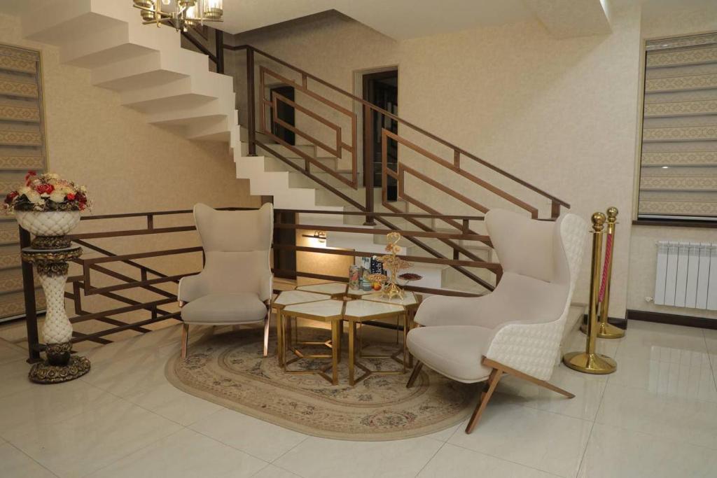 a living room with a table and two chairs and a staircase at Premium Hotel 777 in Tashkent