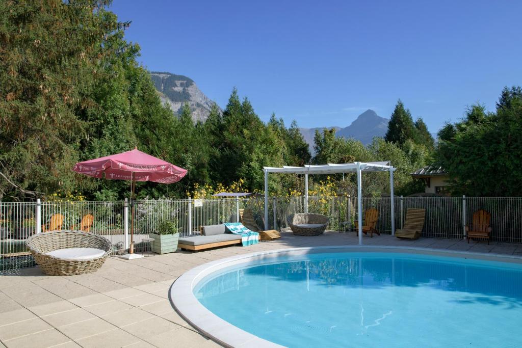 einen Pool mit Sonnenschirm, Stühlen und Sonnenschirm in der Unterkunft Sport'Hotel-Aparthotel de Milan in Le Bourg-dʼOisans