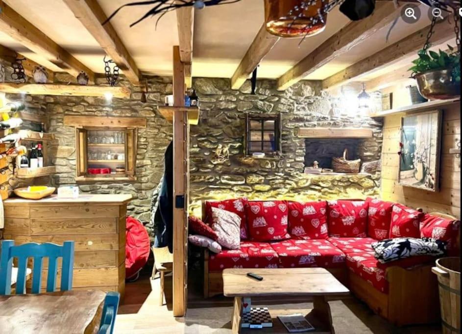 a living room with a red couch and a stone wall at Baita Il Focolare - Your Mountain Holiday in Premana