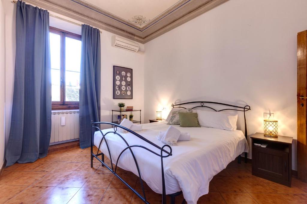 1 dormitorio con 1 cama con sábanas blancas y cortinas azules en Mamo Florence - Pisana Apartment, en Florencia