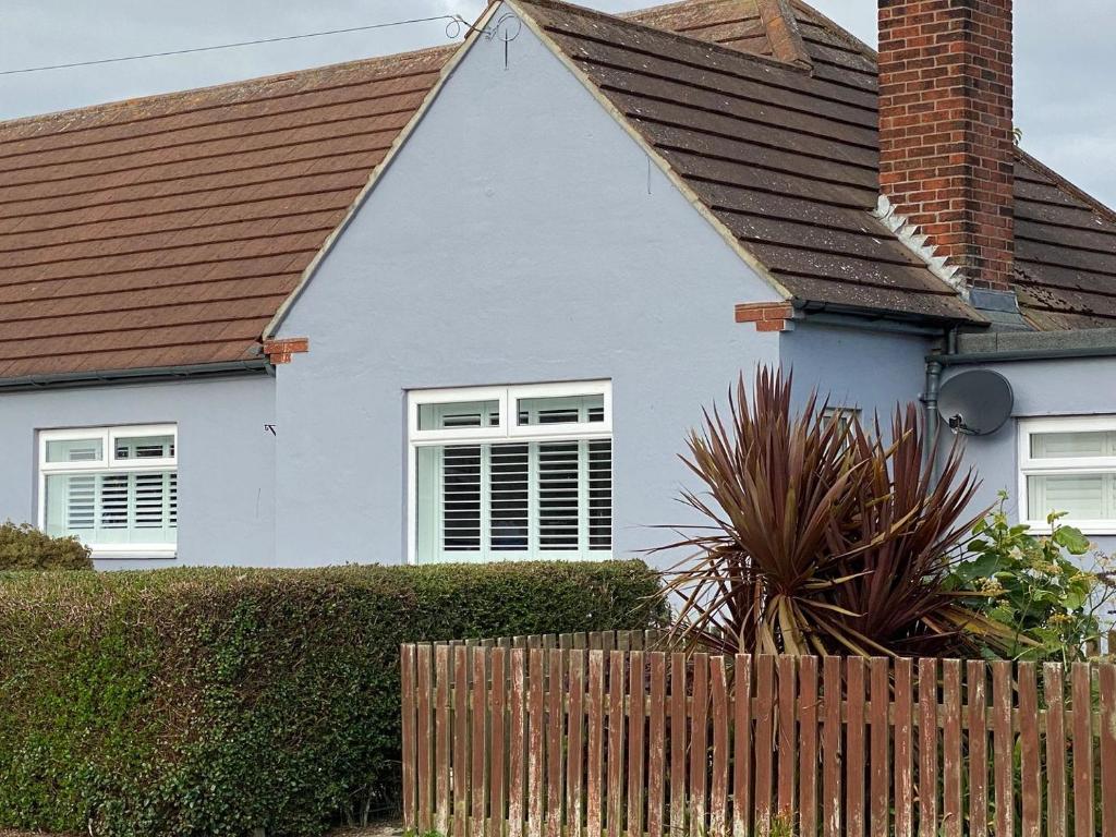 ein weißes Haus mit einem braunen Dach und einem Zaun in der Unterkunft Corner Retreat Holiday Let Seahouses in Seahouses