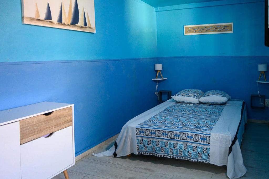 a blue bedroom with a bed with blue walls at Les bungalows meublés du Pharest in Sainte-Suzanne