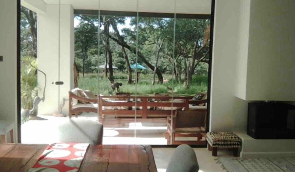 a living room with a sliding glass door with a dog outside at Leopards Hill, Lusaka family home in beautiful nature in Mwambula