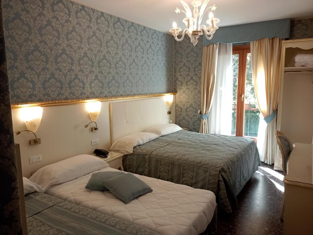 a hotel room with two beds and a chandelier at Hotel Il Mercante di Venezia in Venice