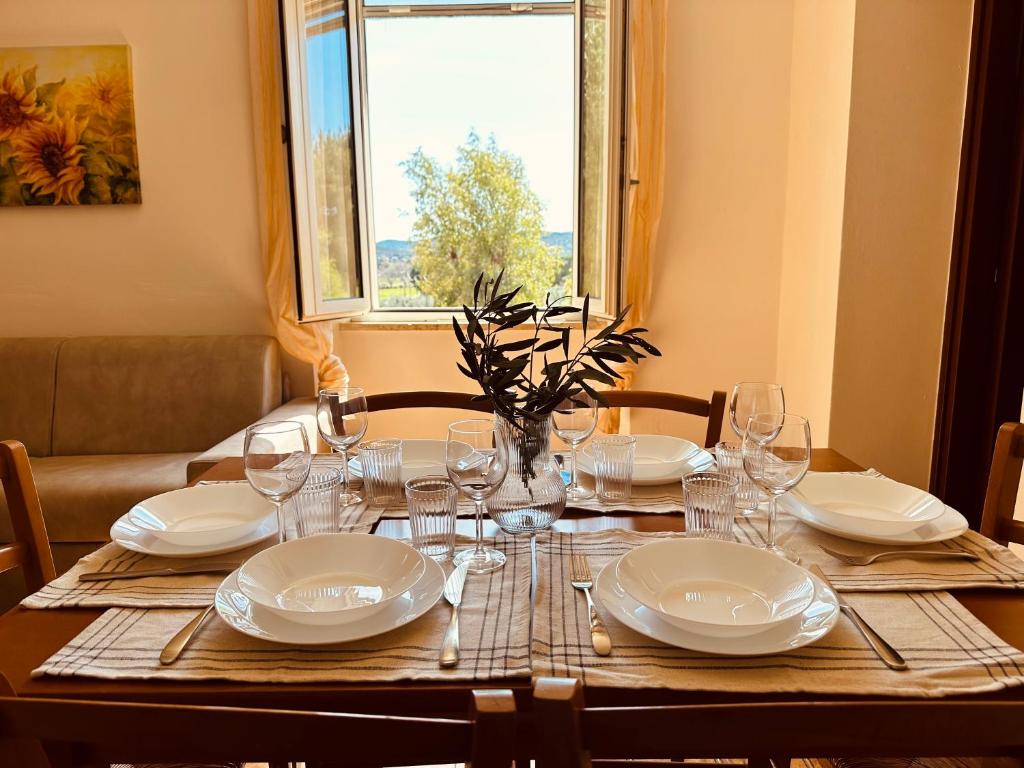 a table with plates and glasses and a window at Agricampeggio La Piaggia - Agriturismo in Piombino