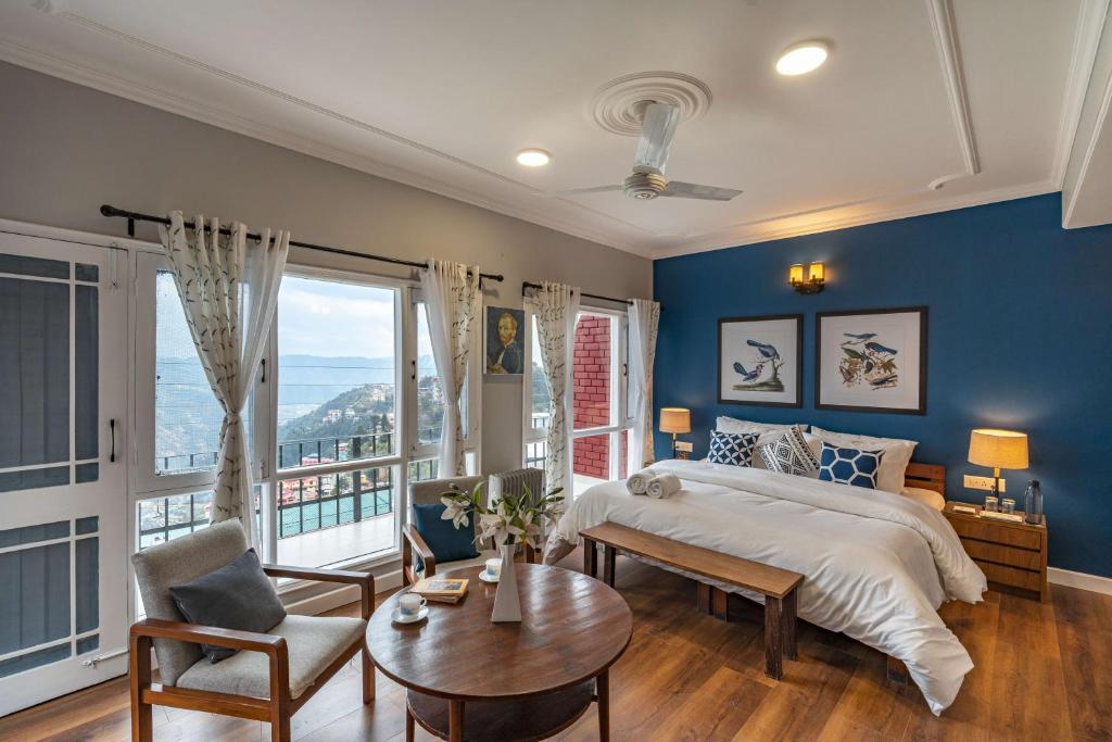 a bedroom with blue walls and a bed and a table at Zostel Homes Shimla in Shimla