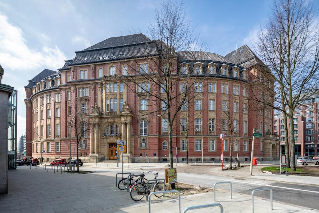 een groot bakstenen gebouw met fietsen voor de deur bij Fraser Suites Hamburg in Hamburg