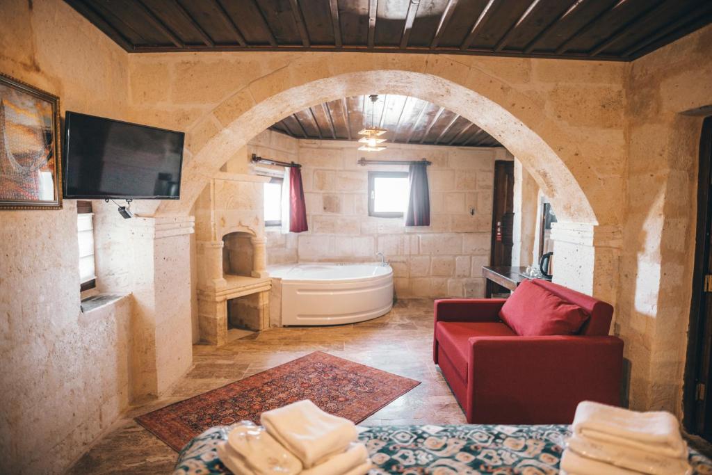 於爾居普的住宿－Tale Cave İnn，客厅配有红色沙发和电视