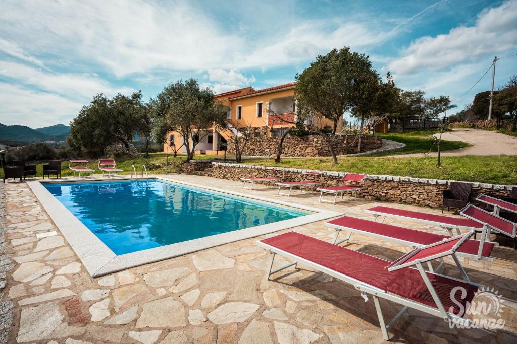 a swimming pool with lounge chairs and a house at Malamuri 5 sun vacanze in Budoni