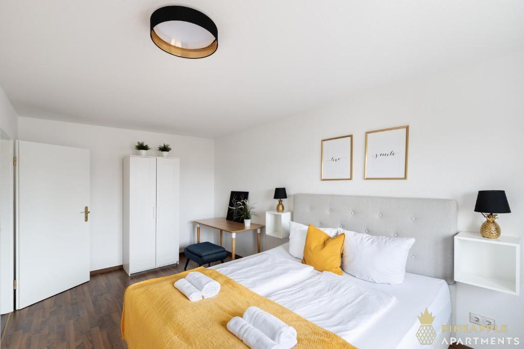 a white bedroom with a large bed with yellow pillows at Pineapple Apartments Dresden Mitte III - free parking in Dresden