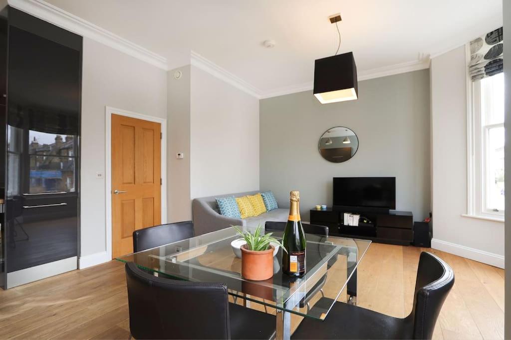 Sala de estar con mesa de cristal y botella de vino en Comfy 1 bed flat in Tufnell Park, en Londres