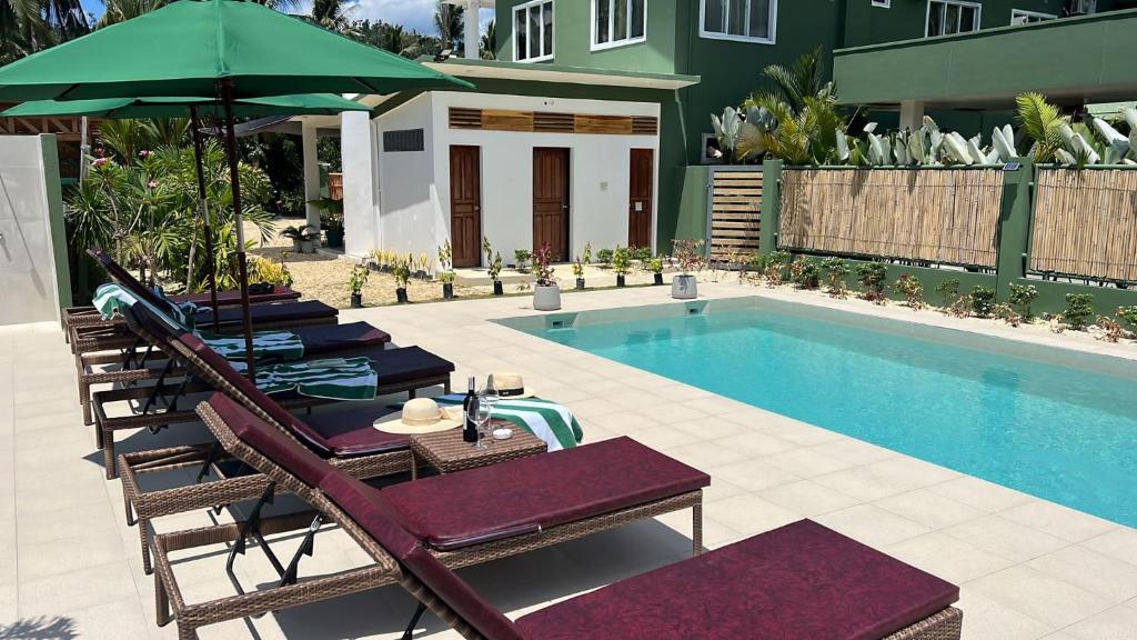 a swimming pool with chairs and a table with an umbrella at ROYAL SUITES - PORT BARTON in San Vicente