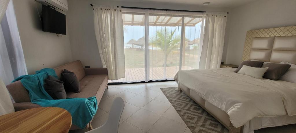 a bedroom with a bed and a couch and a television at Casa Suite Palmar del viento FRENTE, FRENTE AL MAR in Moñitos