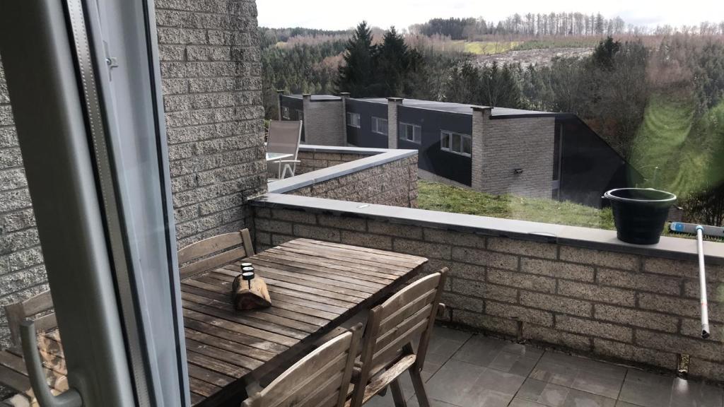 d'un balcon avec une table en bois et une vue sur un bâtiment. dans l'établissement Terrasse de Malmedy 348, à Malmedy