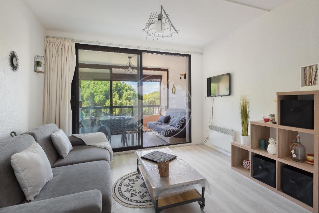 un salon avec un canapé et une table dans l'établissement AS23038 - Studio cabine vue sur Parc avec box, au Grau-du-Roi