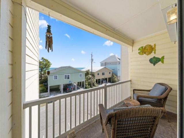 a balcony with two chairs and a table and a window at Breezy Does It - Take it "br-eezy" while you stay in the heart of Carolina Beach, One minute walk to the beach! condo in Carolina Beach