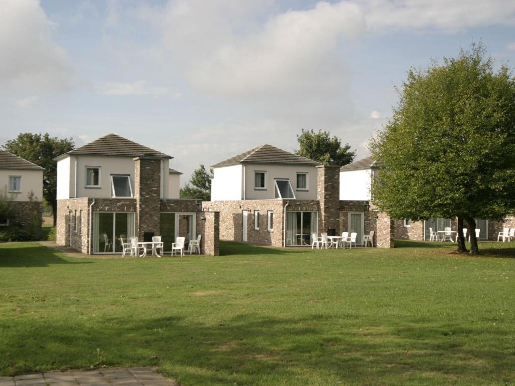 een groot huis met tafels en stoelen in een tuin bij Holiday Home Bungalowpark Landsrade-1 by Interhome in Gulpen