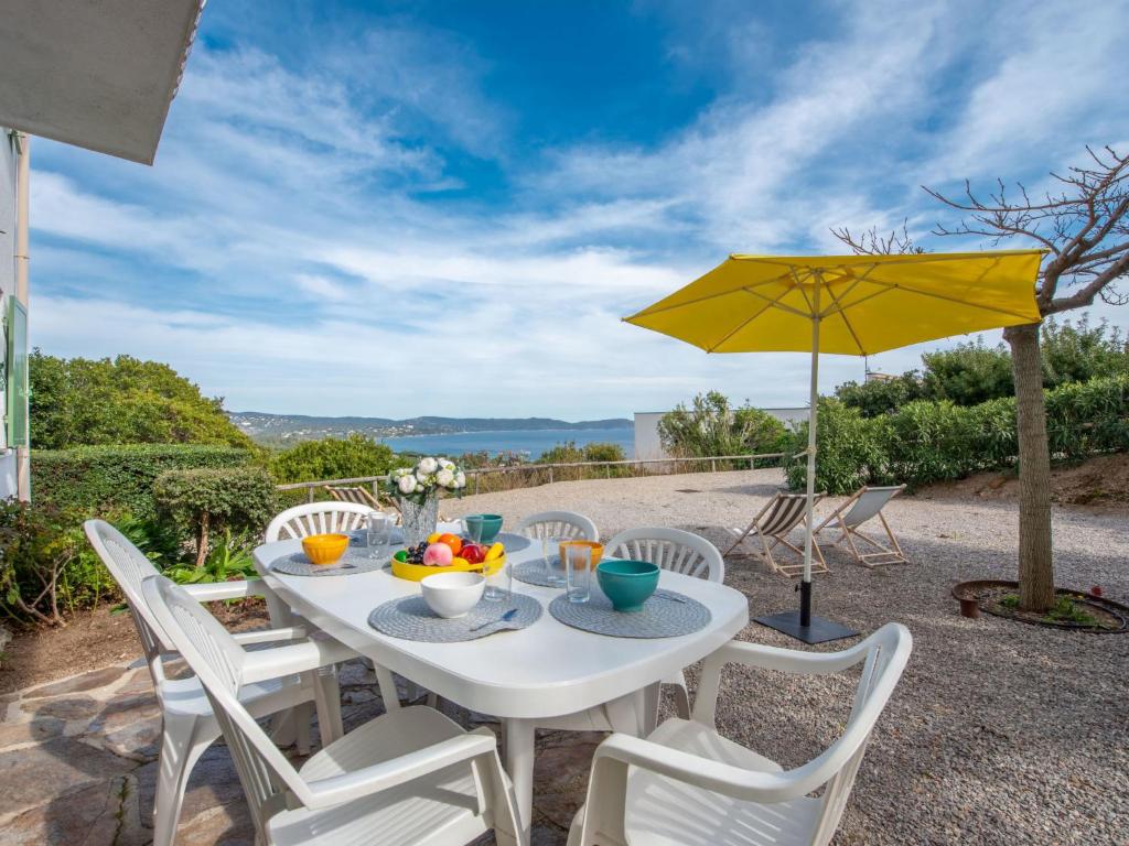 une table blanche avec des chaises et un parapluie jaune dans l'établissement Apartment Les Arbousiers-1 by Interhome, à Cavalaire-sur-Mer