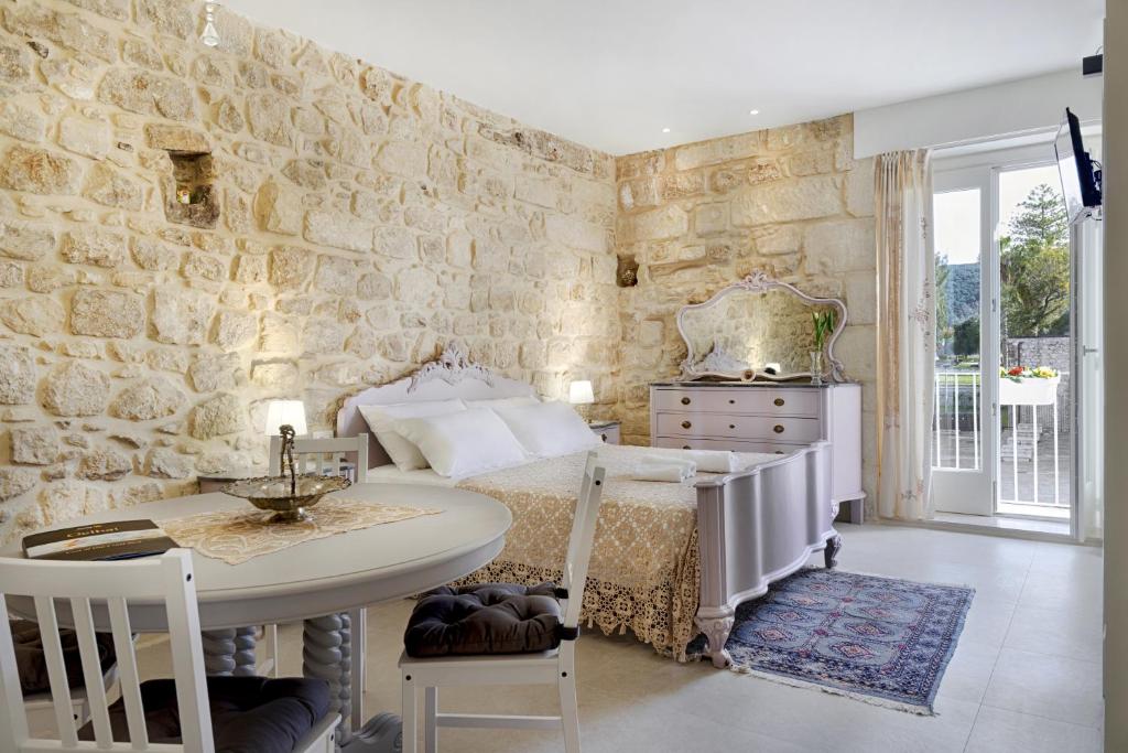 a bedroom with a bed and a table and a stone wall at HyblaLifeRooms in Ragusa