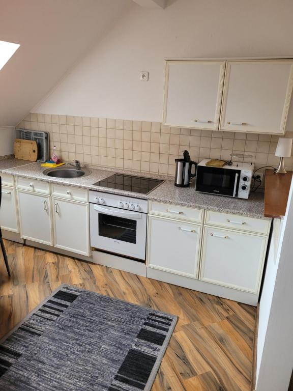 a kitchen with white cabinets and a sink and a microwave at 3 Zimmer Wohnung für 6 Personen in Gößnitz