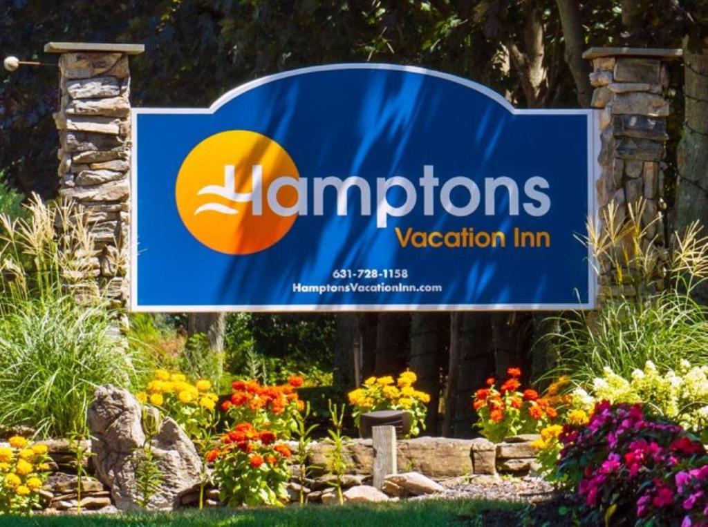 Una señal para la posada de vacaciones Hamptons en un jardín en Hamptons Vacation Inn, en Hampton Bays
