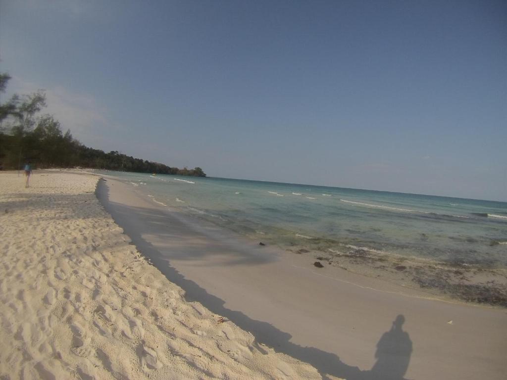 a shadow of a person standing on a beach at Coconutbeach Bungalows in Koh Rong Island