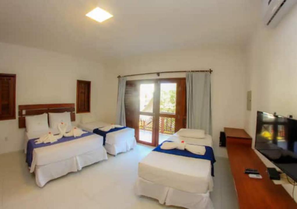 a room with three beds and a flat screen tv at Zion Suítes in Jericoacoara