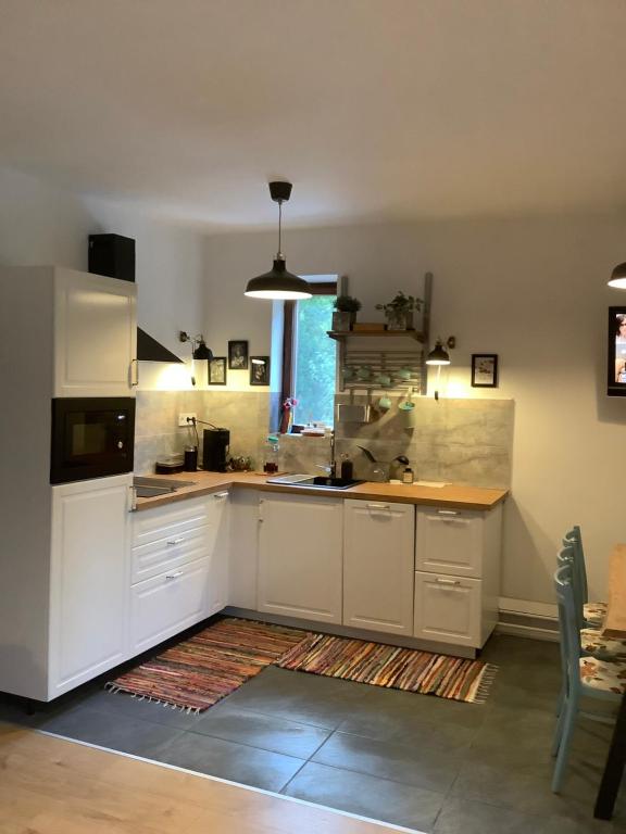 a kitchen with white cabinets and a large window at Borcsa Pihenőház in Mezőkövesd