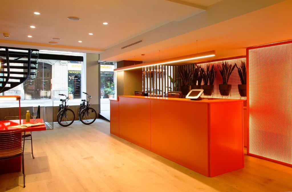 een lobby met een oranje bar en een eetkamer bij chic&basic Reding in Barcelona
